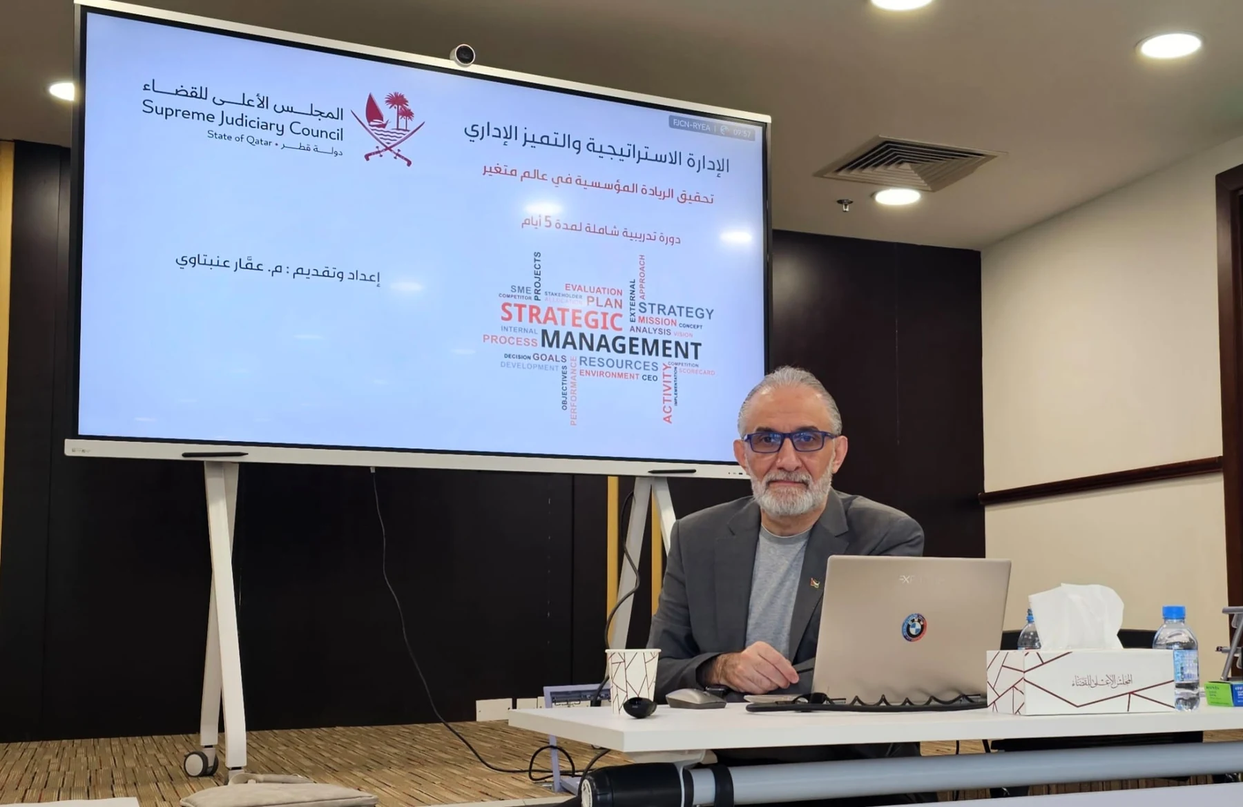 Ammar Anabtawi leading a strategic management training session beside a large presentation display